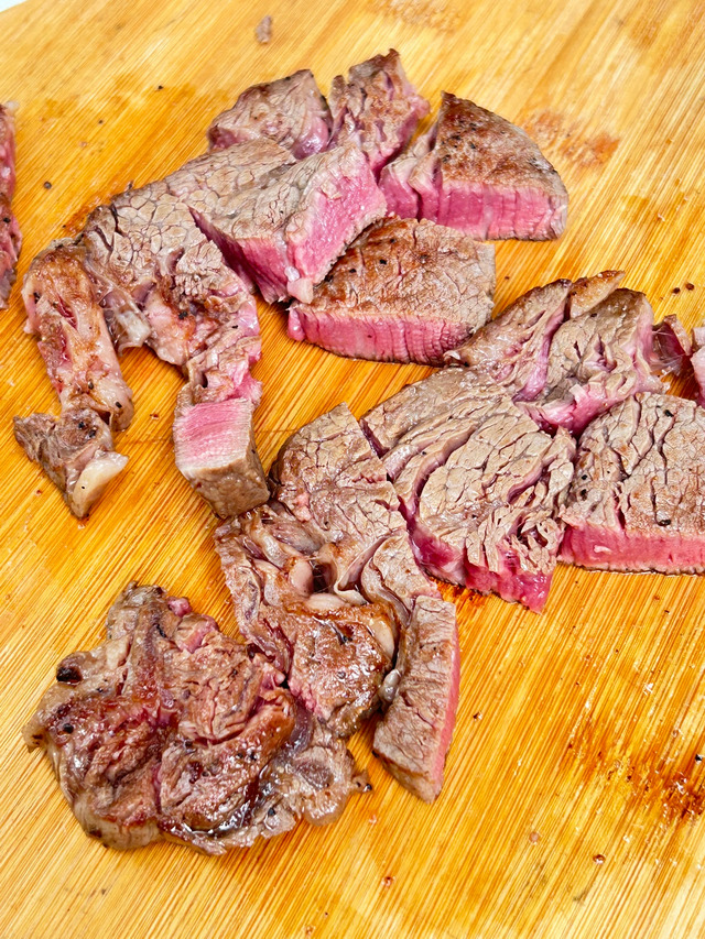 アウトドア活動で焼き上げた、最高級部位シャトーブリアンのステーキ。木製ボードの上で綺麗にカットされた断面が食欲をそそる写真